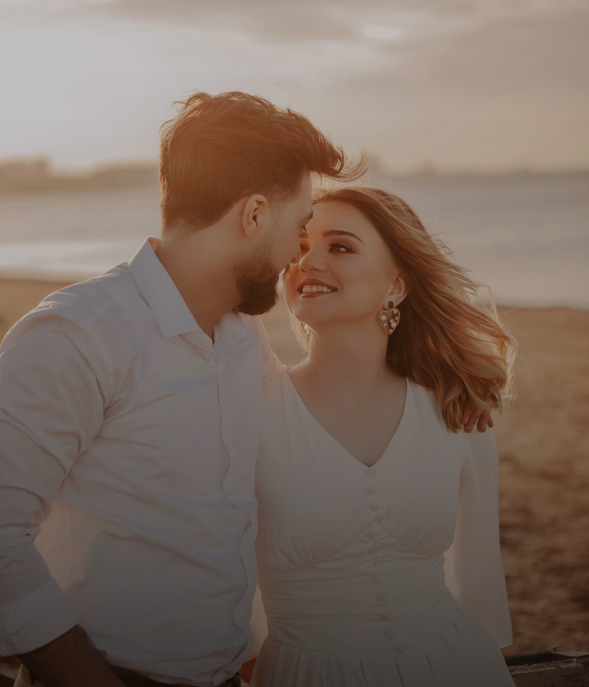 A couple smiling together at sunset on a beach